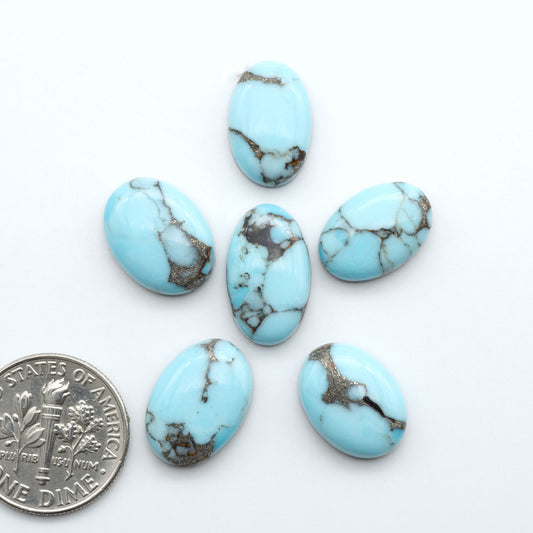 Pressed Turquoise nugget cabochons, composite material with a blue color and dark matrix on a white background, with a US dime for scale.