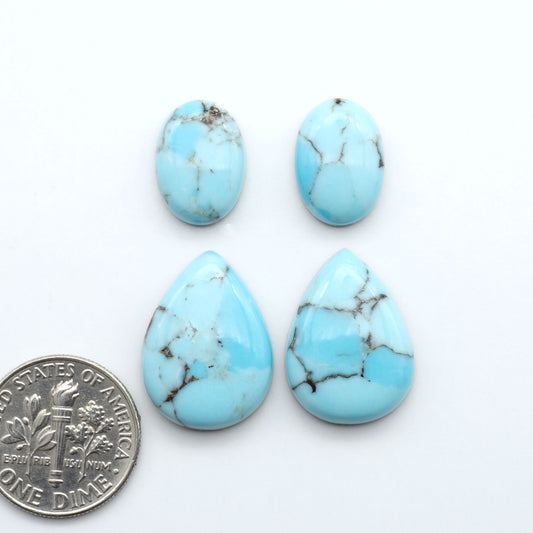 Pressed Turquoise nugget cabochons, composite material with a blue color and dark matrix on a white background, with a US dime for scale.