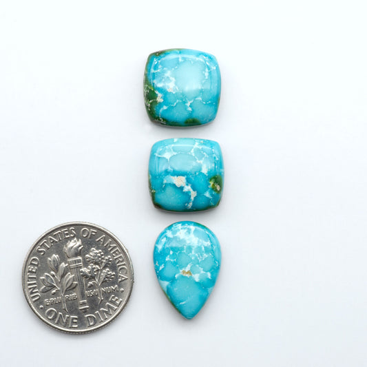 Sonoran Mountain Turquoise cabochons, blue-green color with natural matrix, polished stones on a white background, with a US dime for scale