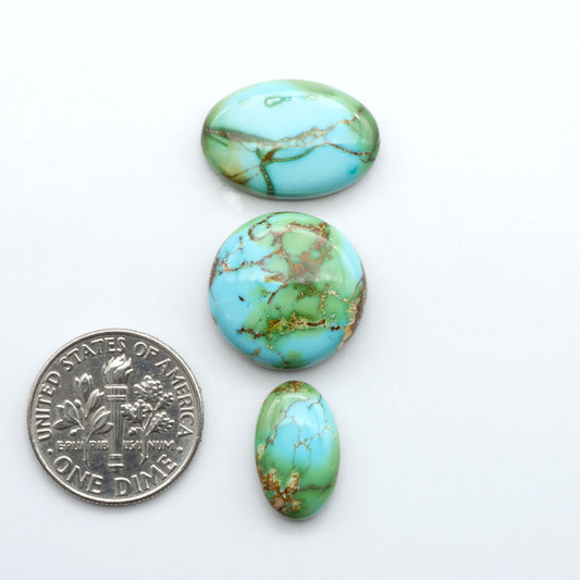 Sonoran Mountain Turquoise cabochons, blue-green color with natural matrix, polished stones on a white background, with a US dime for scale