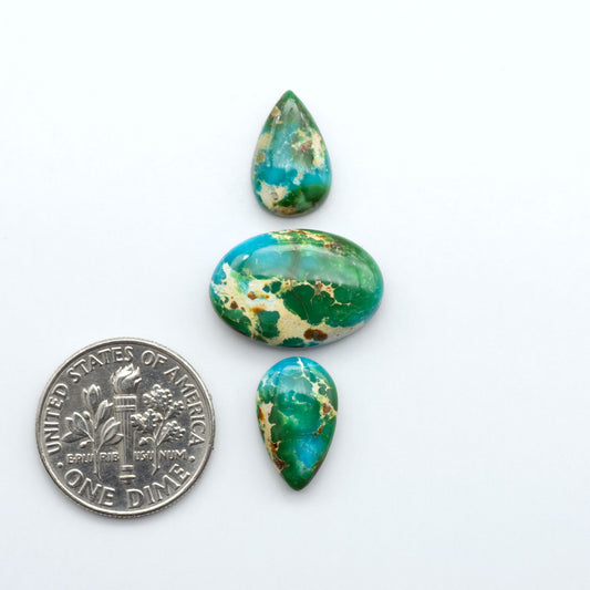 Sonoran Mountain Turquoise cabochons, blue-green color with natural matrix, polished stones on a white background, with a US dime for scale