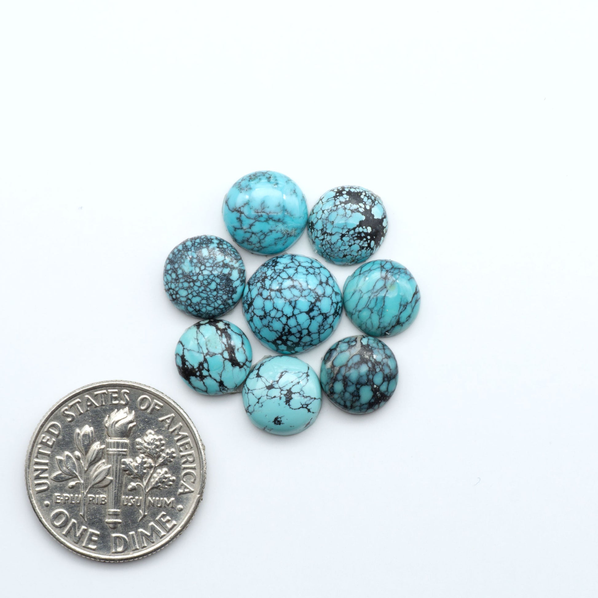 Hubei Cloud Mountain Turquoise cabochons, blue and green color with black matrix, polished stones on a white background with a US dime for scale