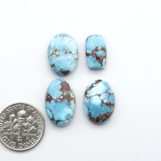 Golden Hills Turquoise cabochons, icy blue to lavender tones with chocolate matrix, polished stones on a white background with a US dime for scale