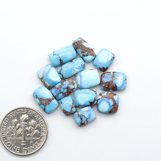 Golden Hills Turquoise cabochons, icy blue to lavender tones with chocolate matrix, polished stones on a white background with a US dime for scale