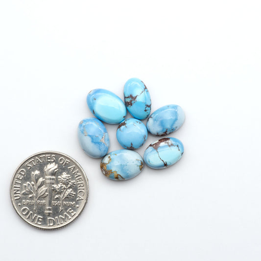 Golden Hills Turquoise cabochons, icy blue to lavender tones with chocolate matrix, polished stones on a white background with a US dime for scale