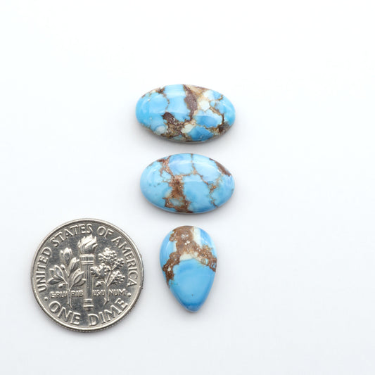 Golden Hills Turquoise cabochons, icy blue to lavender tones with chocolate matrix, polished stones on a white background with a US dime for scale