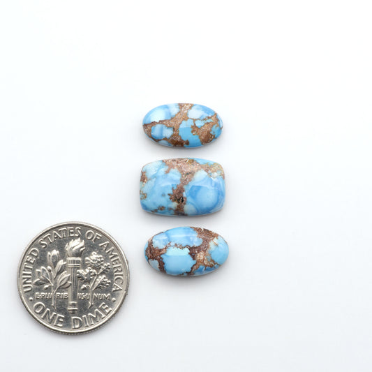 Golden Hills Turquoise cabochons, icy blue to lavender tones with chocolate matrix, polished stones on a white background with a US dime for scale