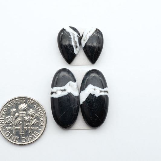 White Buffalo stone cabochons, white stone with black matrix, polished stones on a white background, with a US dime for scale