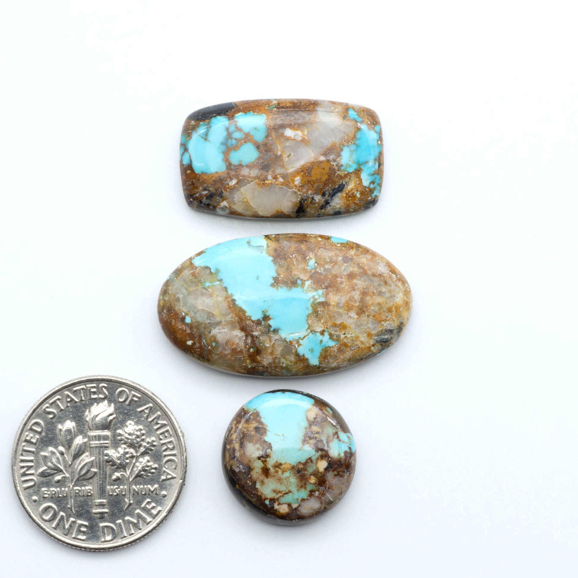 Black Jack Turquoise cabochons, blue-green color with black matrix, polished stones on a white background, with a US dime for scale
