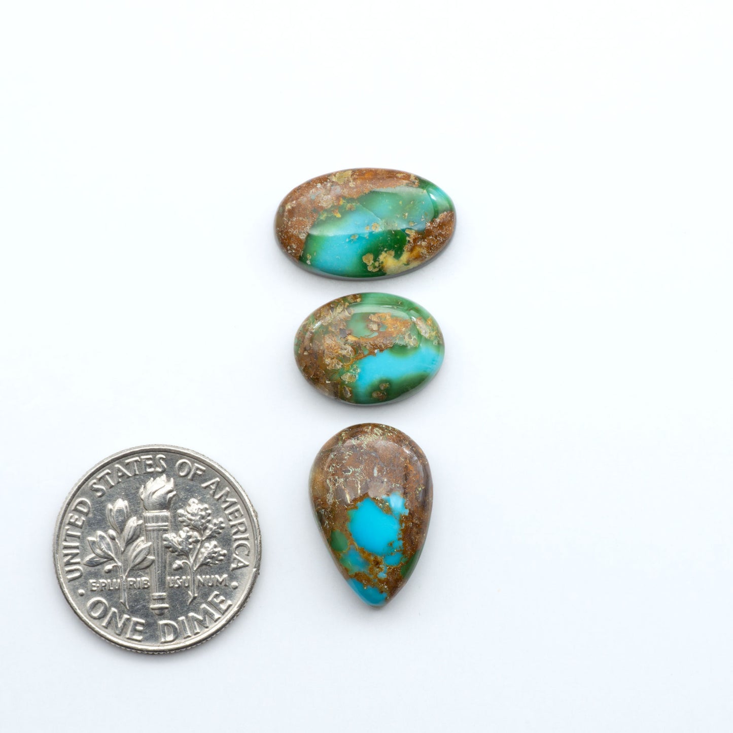 Sonoran Mountain Turquoise cabochons, blue-green color with natural matrix, polished stones on a white background, with a US dime for scale
