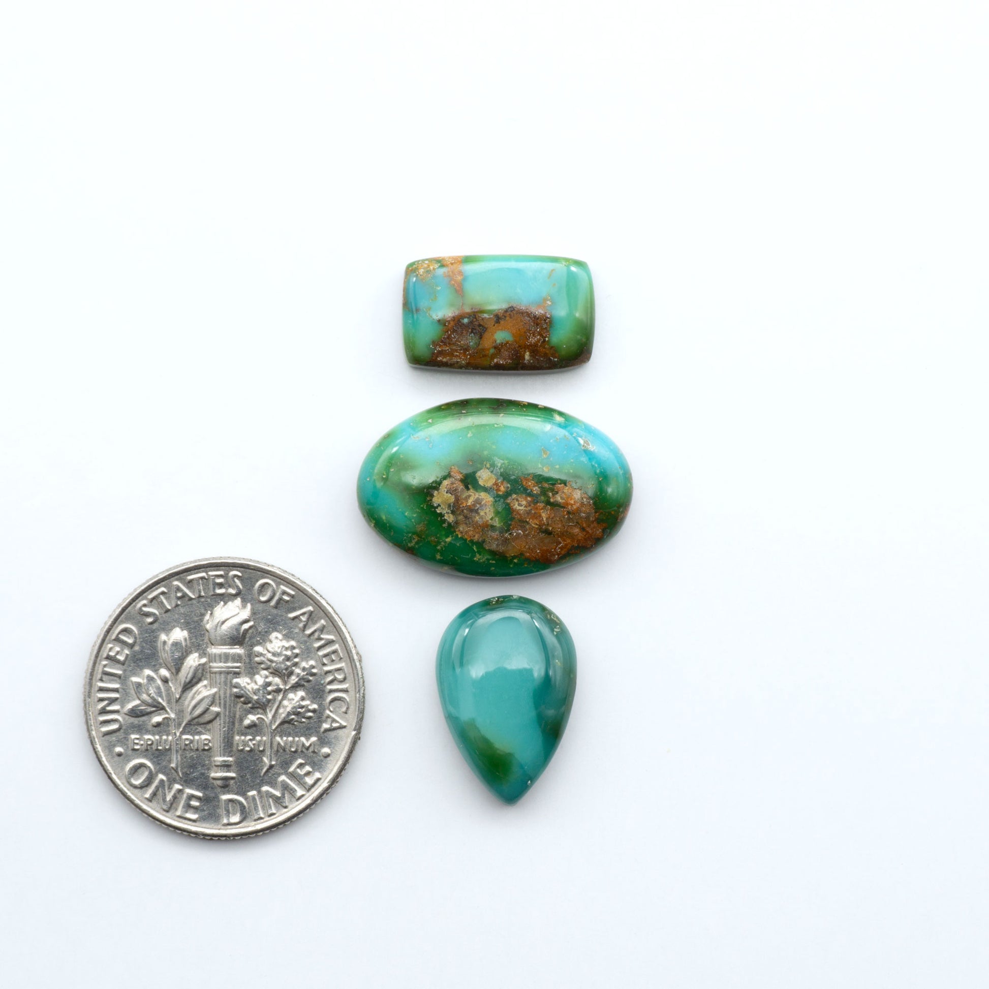 Sonoran Mountain Turquoise cabochons, blue-green color with natural matrix, polished stones on a white background, with a US dime for scale