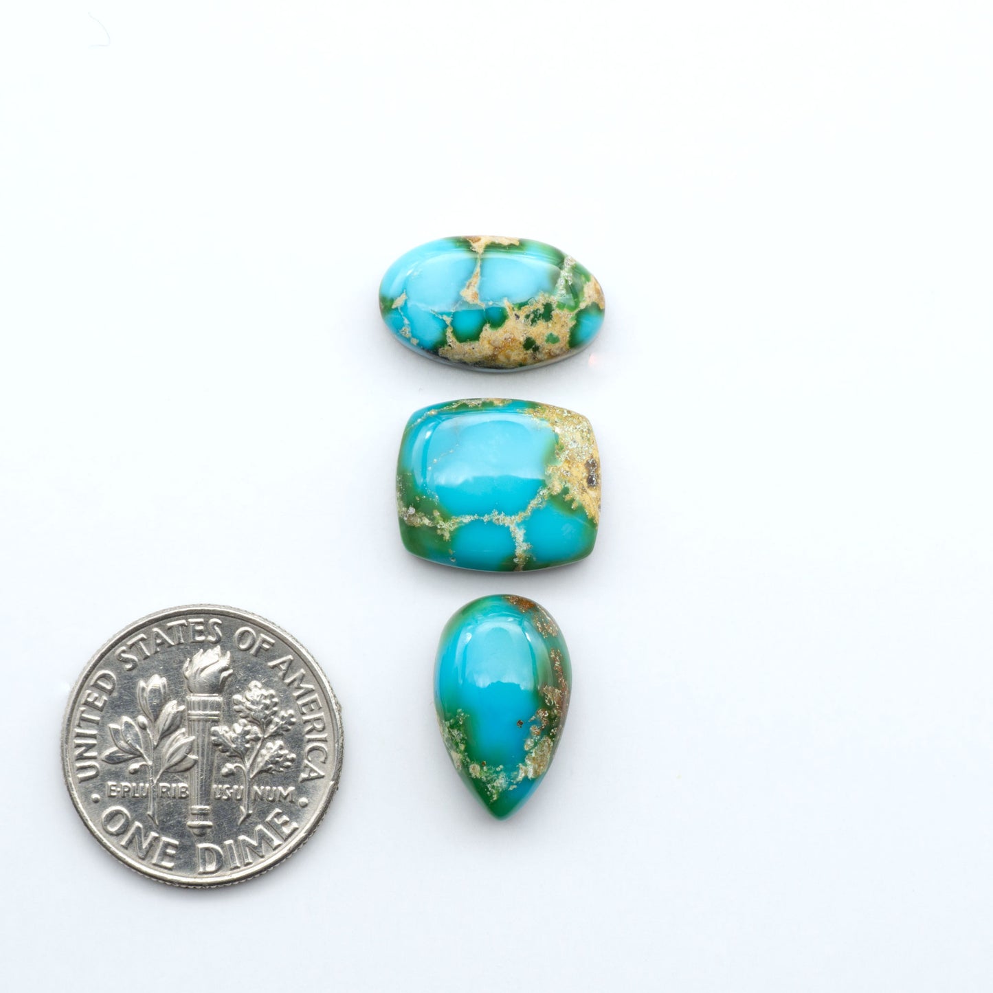 Sonoran Mountain Turquoise cabochons, blue-green color with natural matrix, polished stones on a white background, with a US dime for scale
