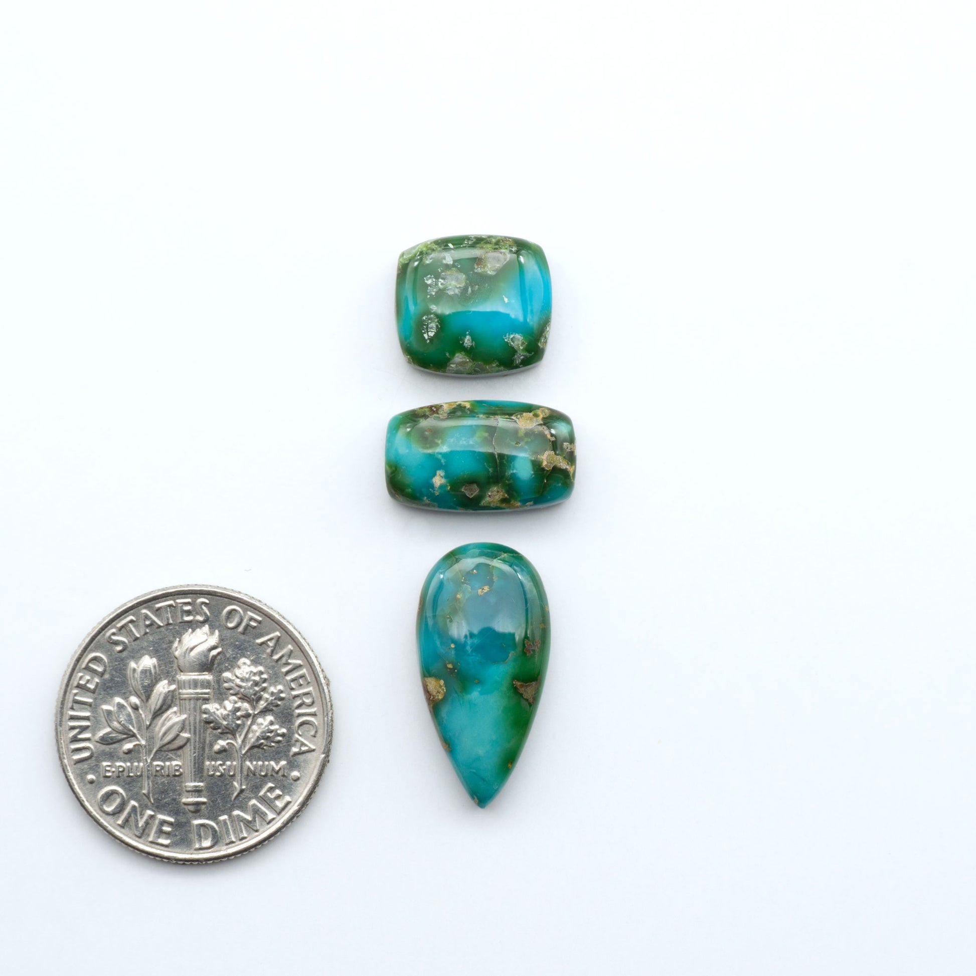 Sonoran Mountain Turquoise cabochons, blue-green color with natural matrix, polished stones on a white background, with a US dime for scale