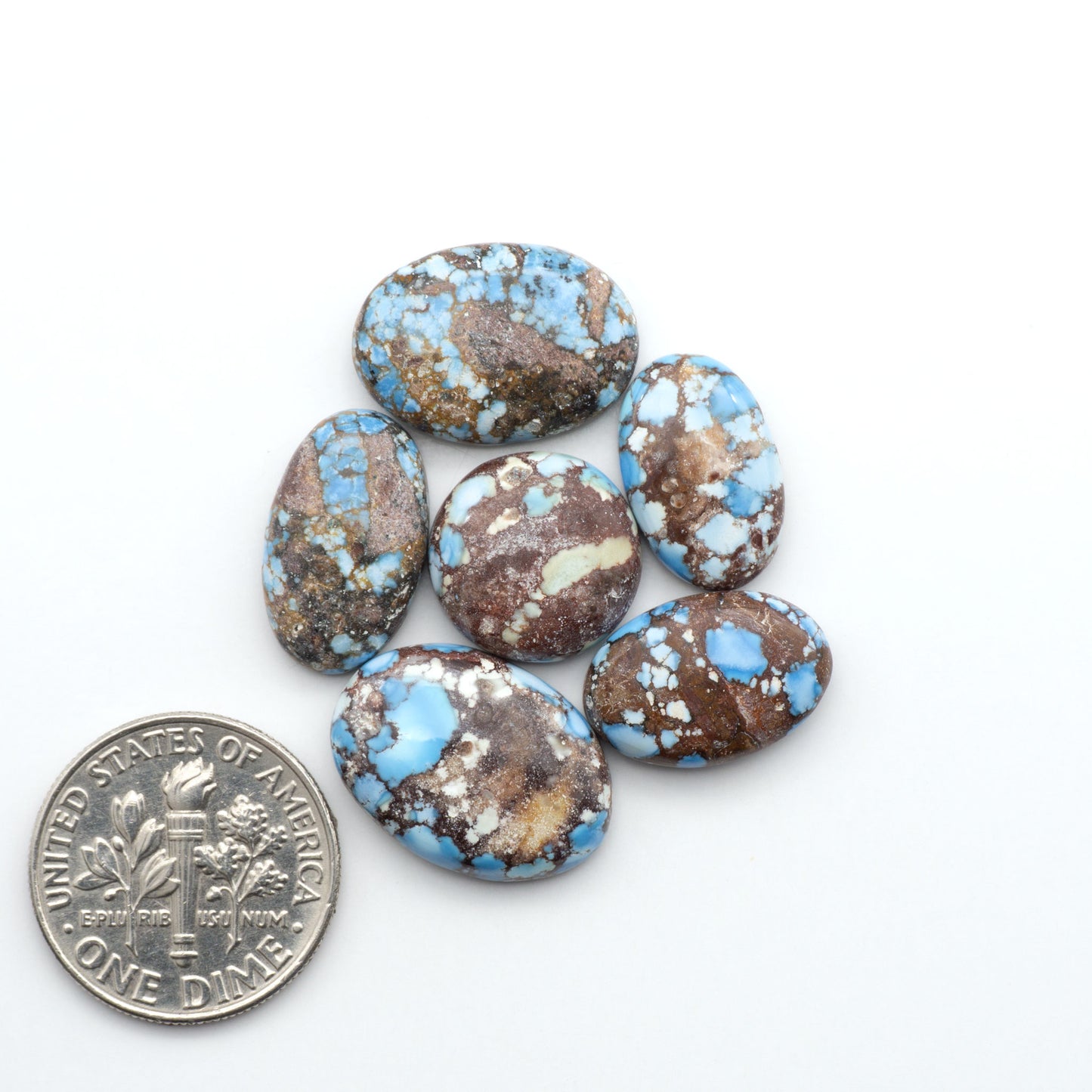 Golden Hills Turquoise cabochons, icy blue to lavender tones with chocolate matrix, polished stones on a white background with a US dime for scale
