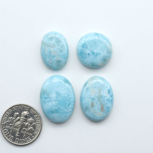 Larimar stone cabochons, cut and polished, blue and white gemstones on a white background, with a US dime for scale