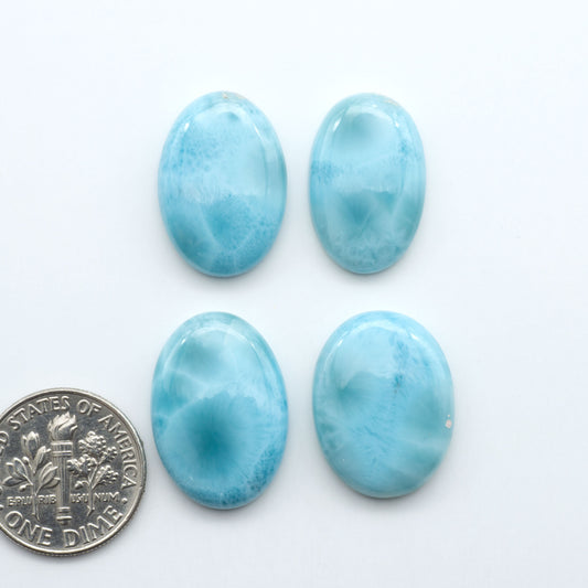 Larimar stone cabochons, cut and polished, blue and white gemstones on a white background, with a US dime for scale