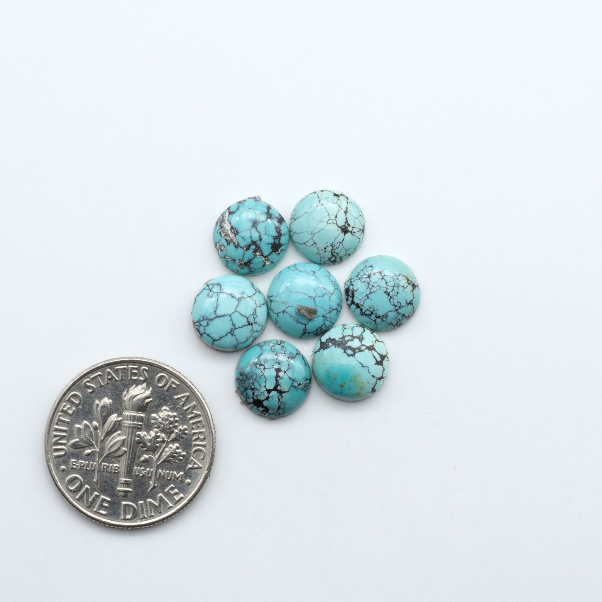 Hubei Cloud Mountain Turquoise cabochons, blue and green color with black matrix, polished stones on a white background, with a US dime for scale