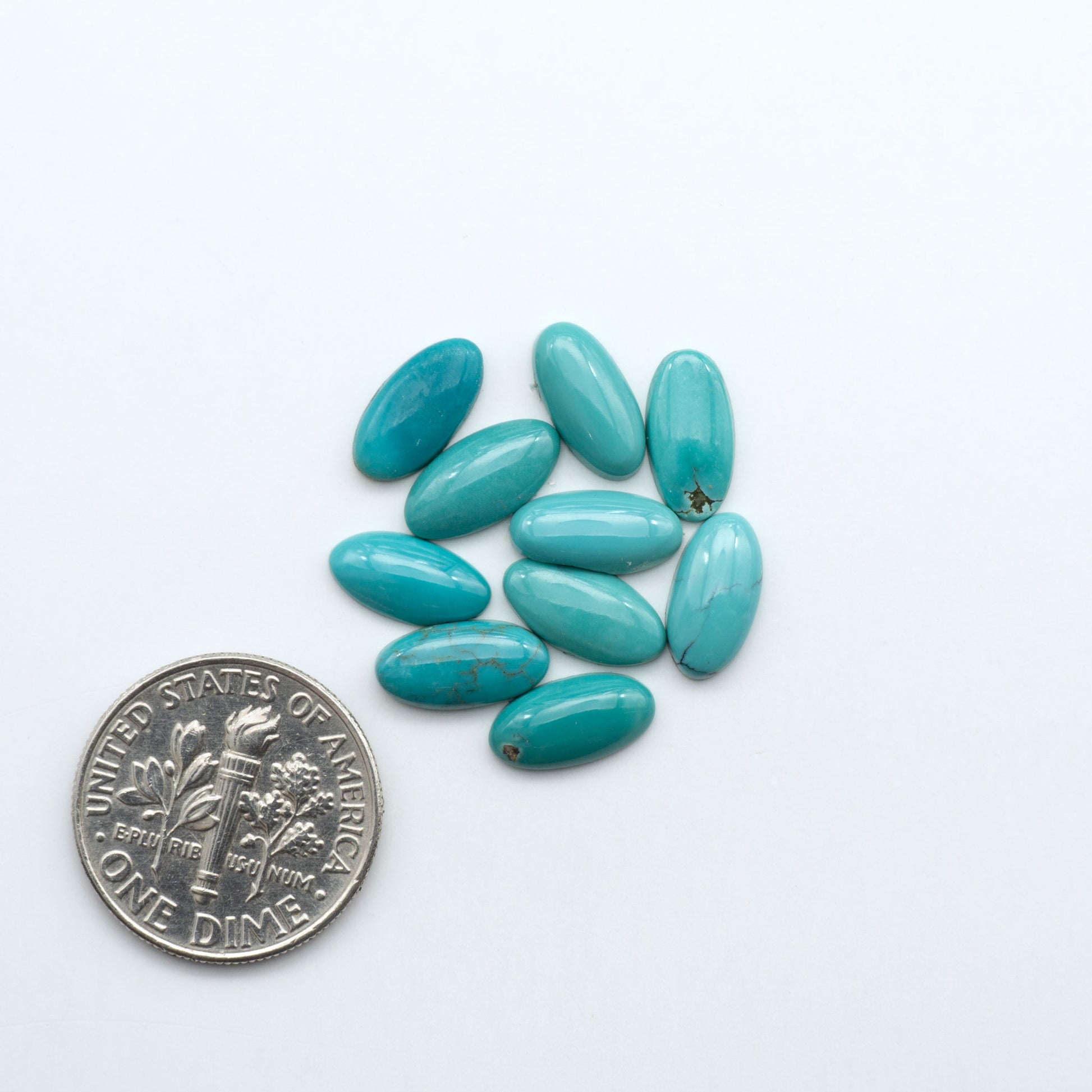 Hubei Cloud Mountain Turquoise cabochons, blue and green color with black matrix, polished stones on a white background, with a US dime for scale