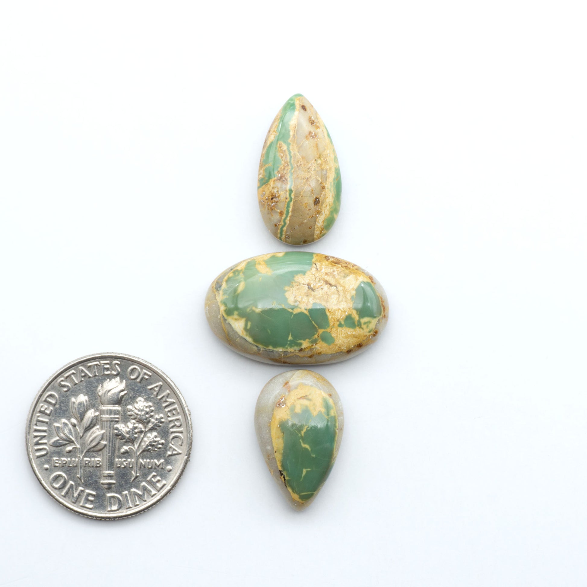Royston Turquoise cabochons, blue-green color with natural matrix, polished stones on a white background, with a US dime for scale