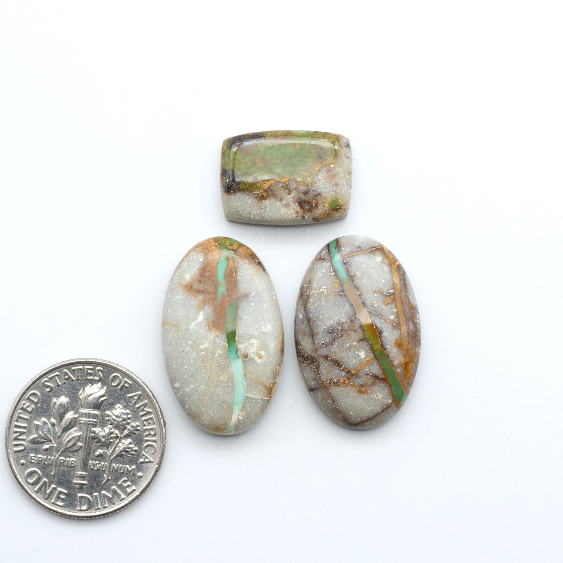 Royston Turquoise cabochons, blue-green color with natural matrix, polished stones on a white background, with a US dime for scale