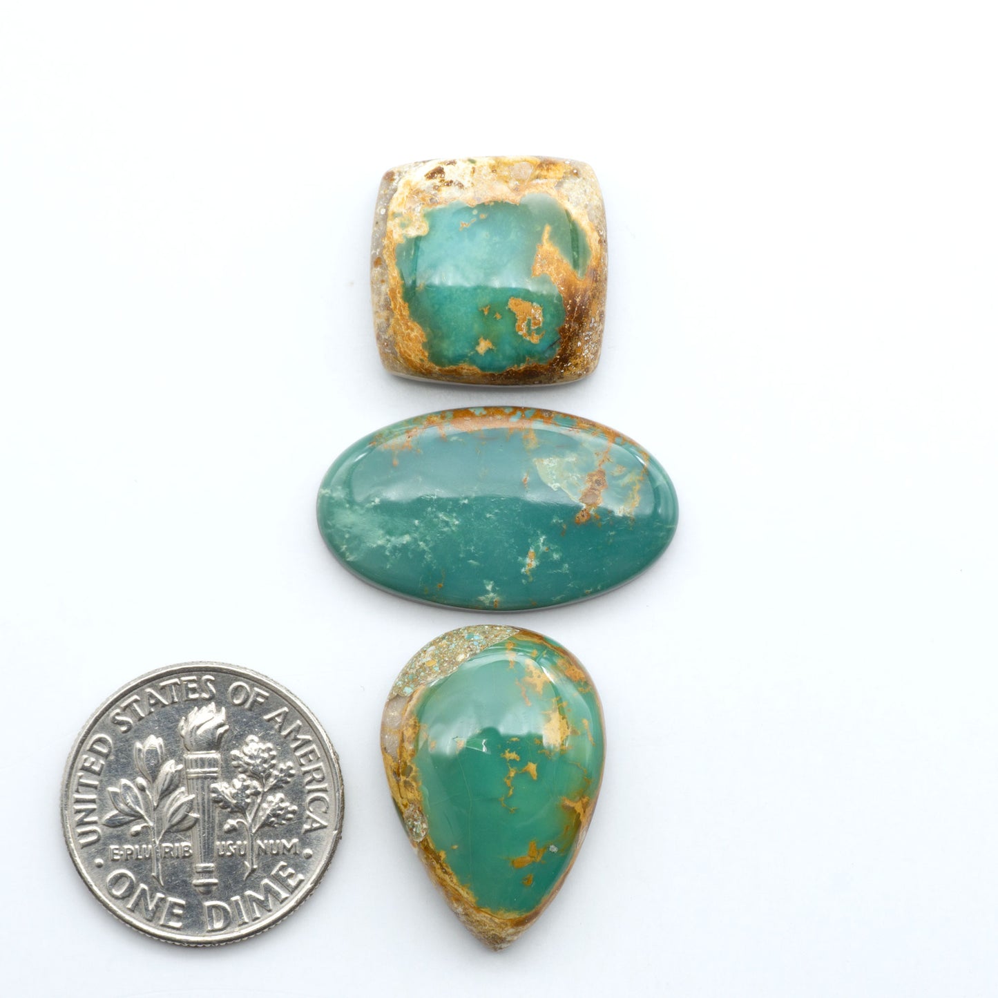 Royston Turquoise cabochons, blue-green color with natural matrix, polished stones on a white background, with a US dime for scale
