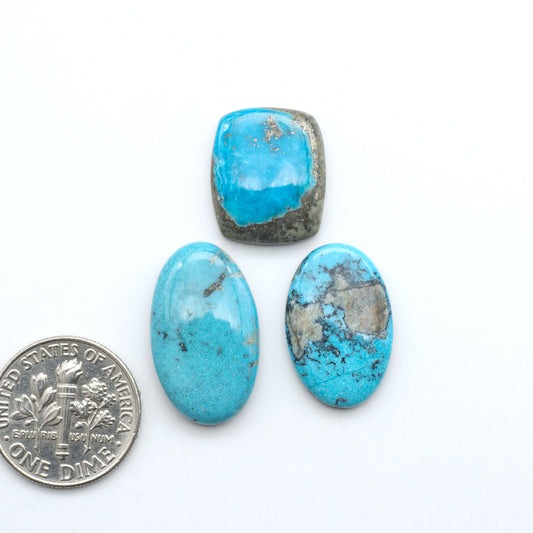 Royston Turquoise cabochons, blue-green color with natural matrix, polished stones on a white background, with a US dime for scale