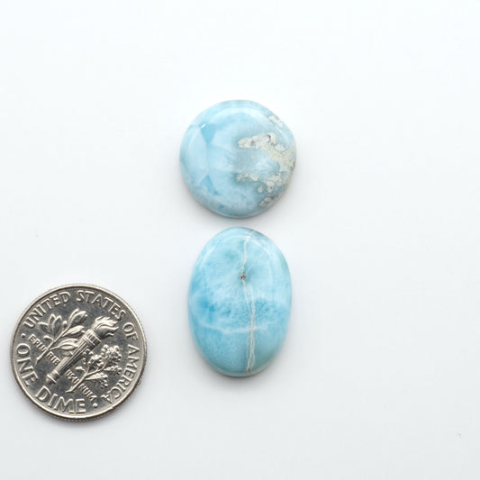 Larimar stone cabochons, cut and polished, blue and white gemstones on a white background, with a US dime for scale