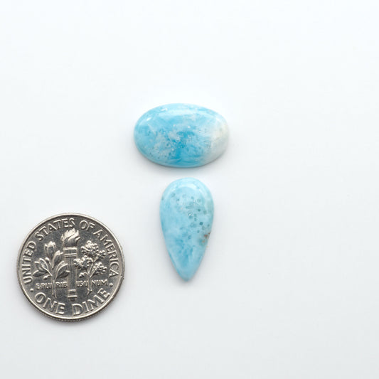 Larimar stone cabochons, cut and polished, blue and white gemstones on a white background, with a US dime for scale