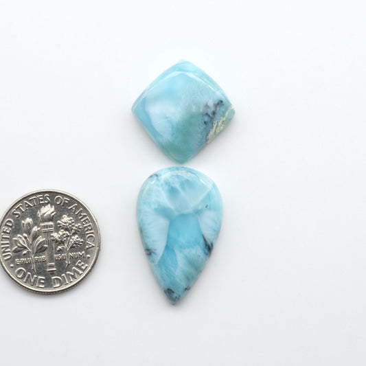 Larimar stone cabochons, cut and polished, blue and white gemstones on a white background, with a US dime for scale