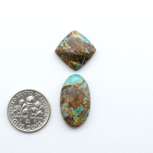 Black Jack Turquoise cabochons, blue-green color with black matrix, polished stones on a white background, with a US dime for scale