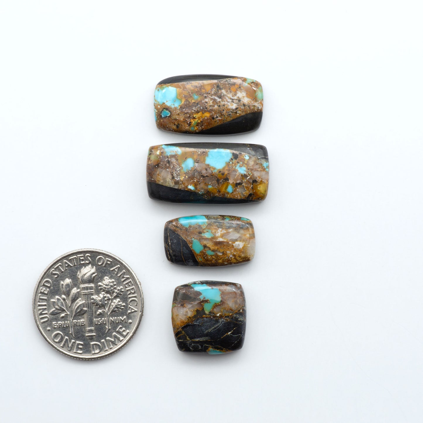 Black Jack Turquoise cabochons, blue-green color with black matrix, polished stones on a white background, with a US dime for scale