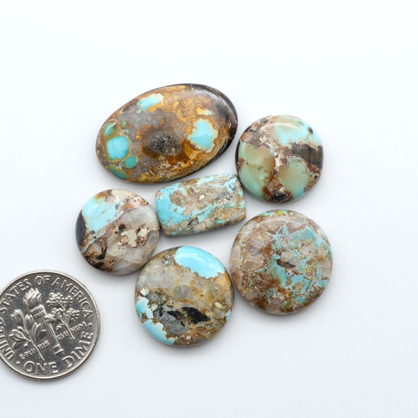 Black Jack Turquoise cabochons, blue-green color with black matrix, polished stones on a white background, with a US dime for scale