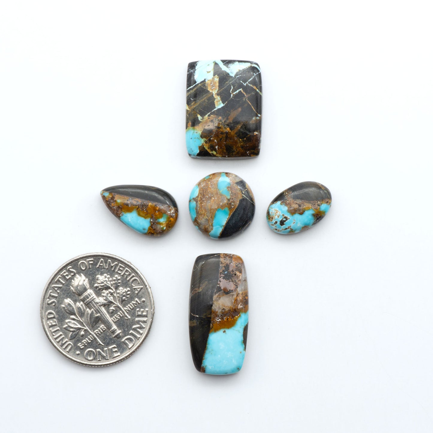 Black Jack Turquoise cabochons, blue-green color with black matrix, polished stones on a white background, with a US dime for scale