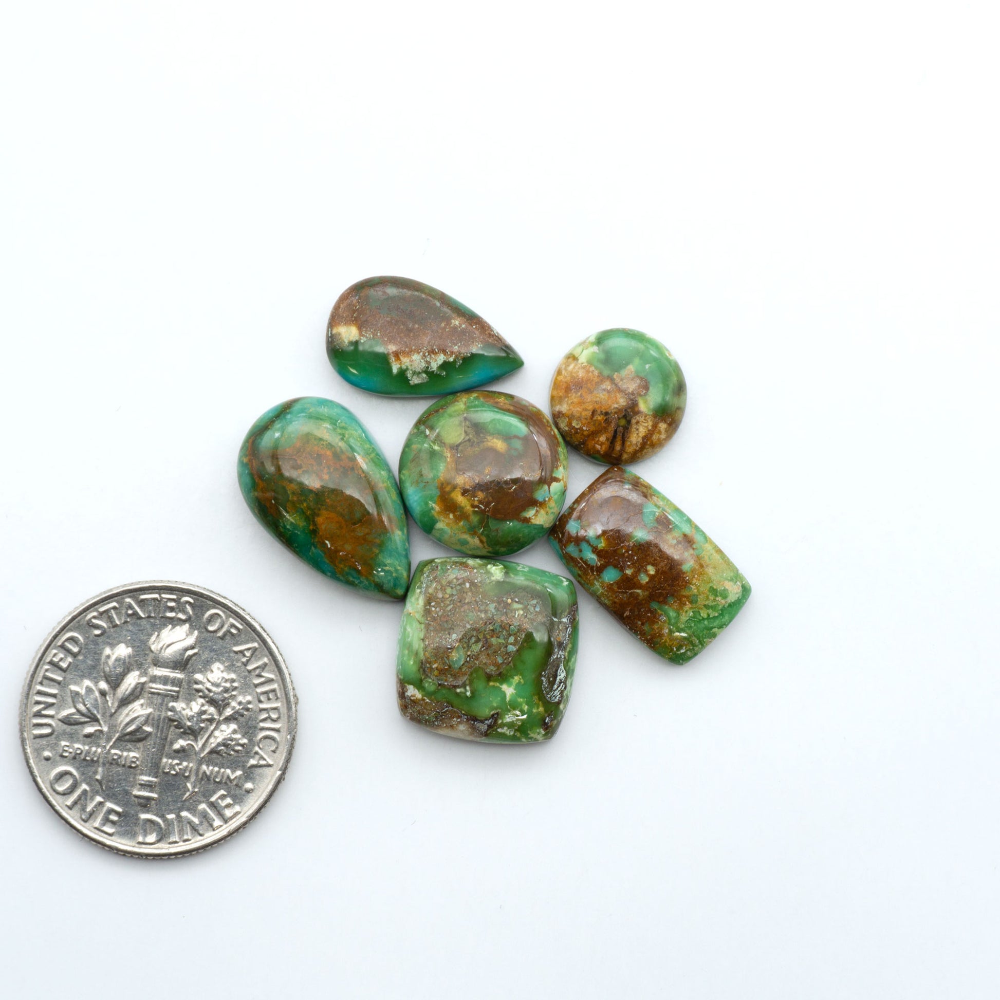 Sonoran Mountain Turquoise cabochons, blue-green color with natural matrix, polished stones on a white background, with a US dime for scale