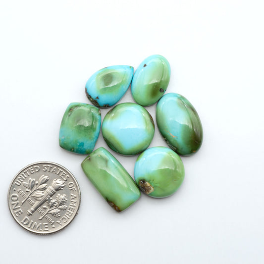 Sonoran Mountain Turquoise cabochons, blue-green color with natural matrix, polished stones on a white background, with a US dime for scale