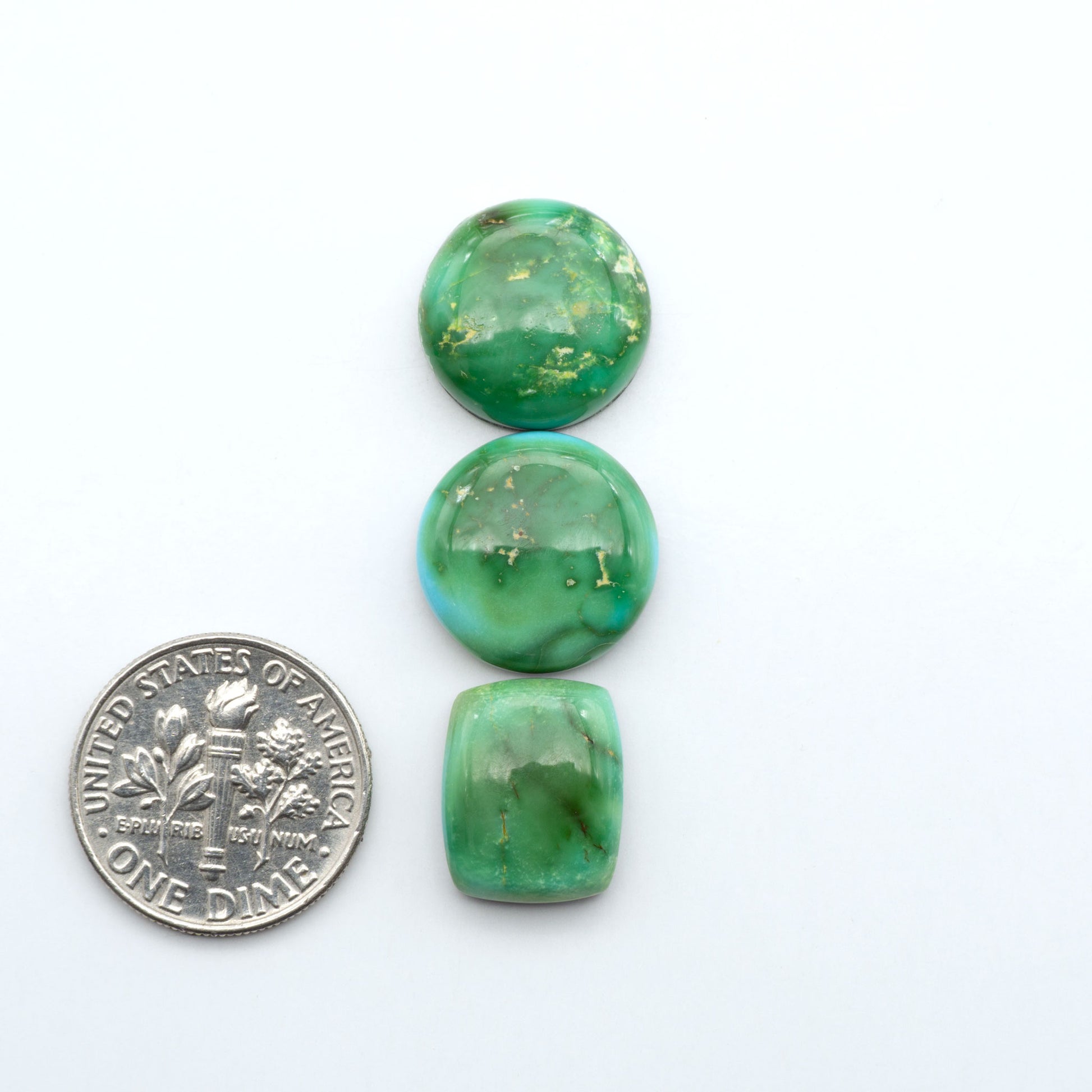 Sonoran Mountain Turquoise cabochons, blue-green color with natural matrix, polished stones on a white background, with a US dime for scale