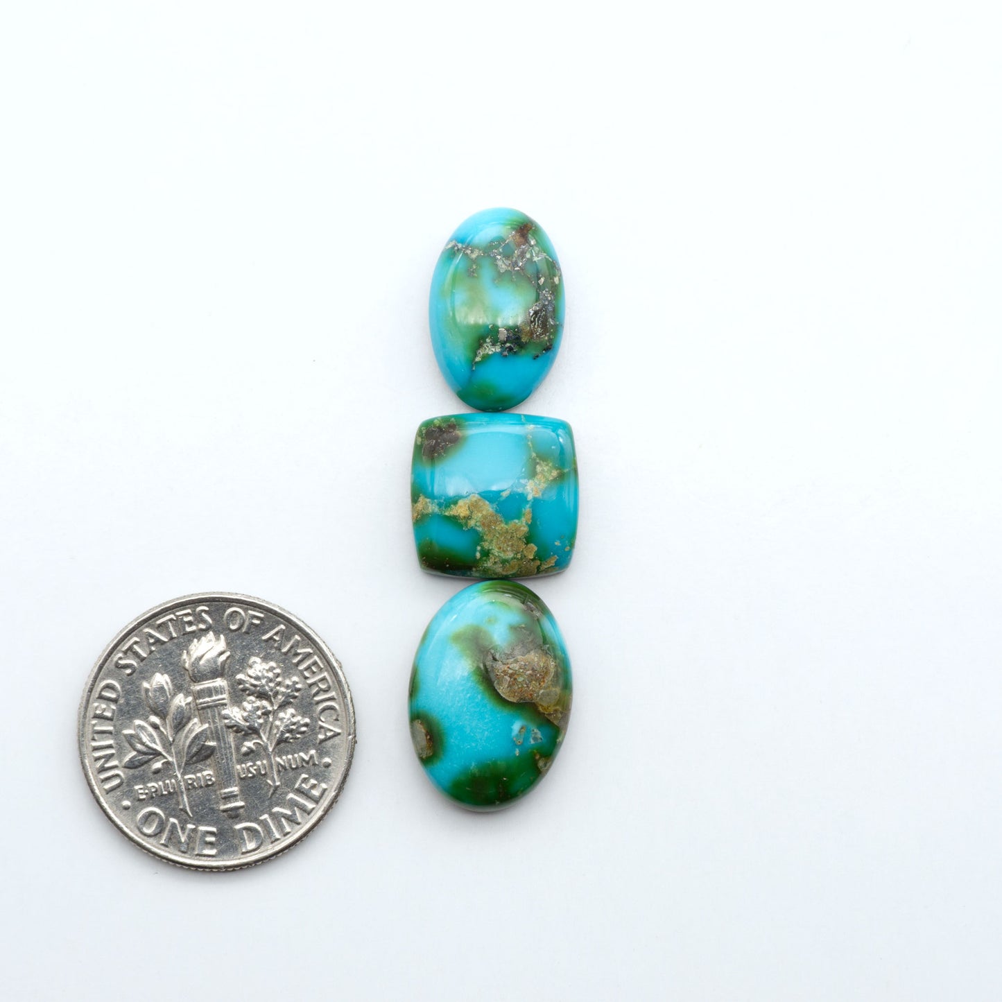 Sonoran Mountain Turquoise cabochons, blue-green color with natural matrix, polished stones on a white background, with a US dime for scale