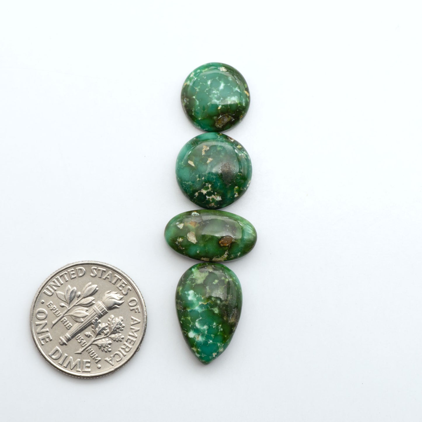 Sonoran Mountain Turquoise cabochons, blue-green color with natural matrix, polished stones on a white background, with a US dime for scale