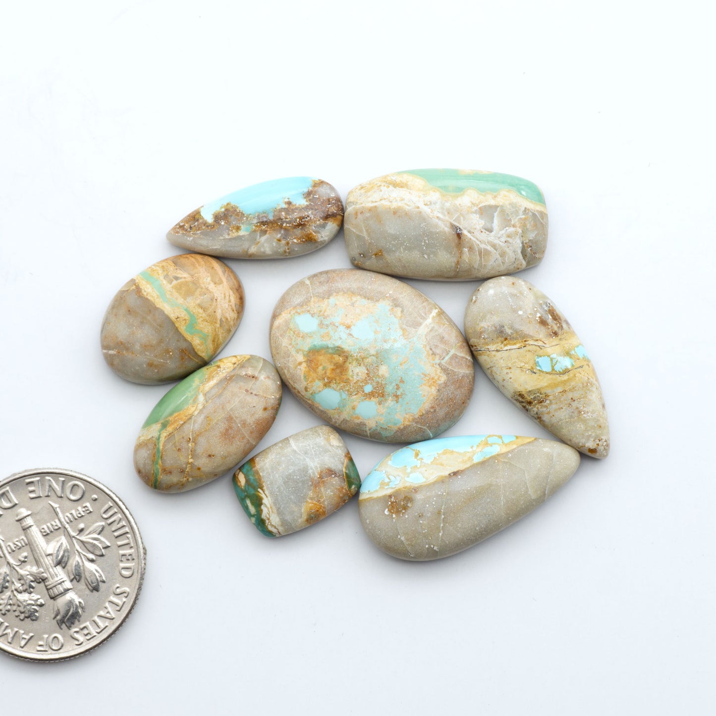 Royston Turquoise cabochons, blue-green color with natural matrix, polished stones on a white background, with a US dime for scale