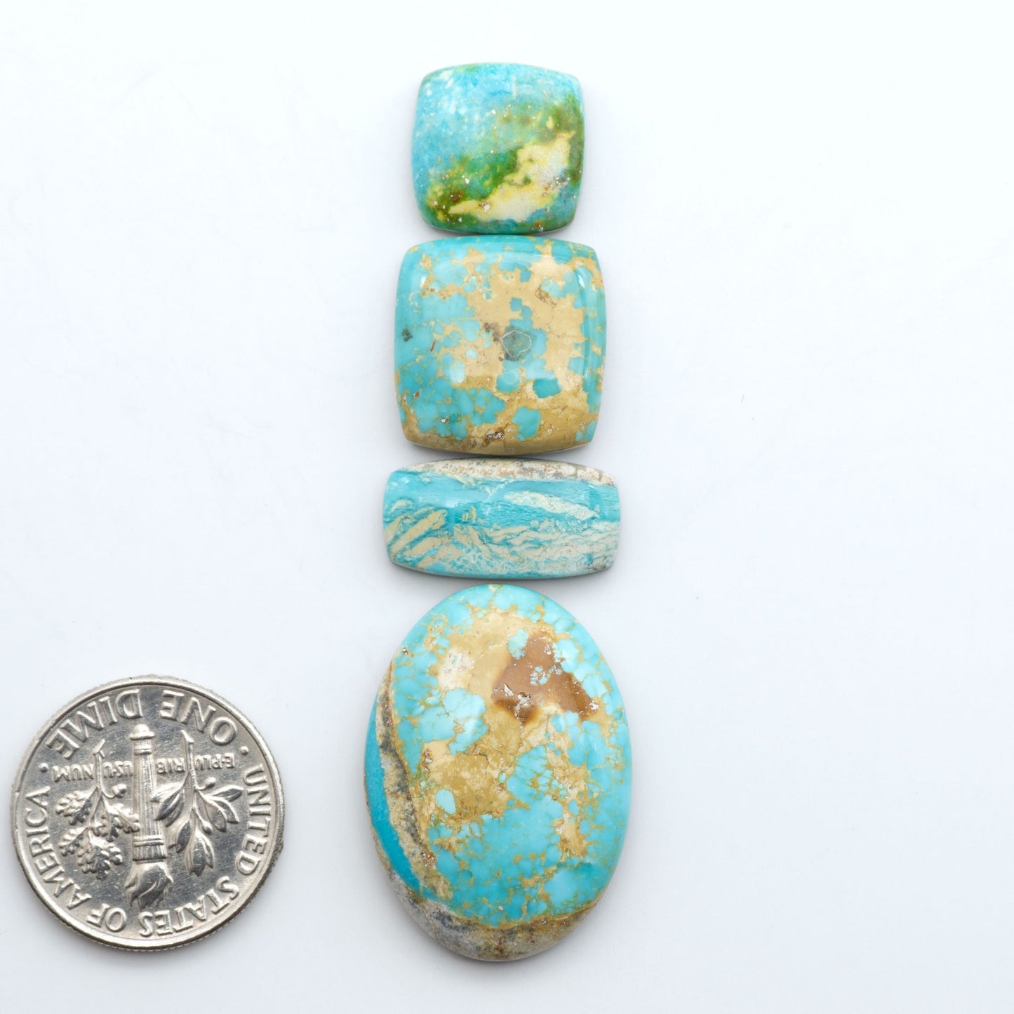 Royston Turquoise cabochons, blue-green color with natural matrix, polished stones on a white background, with a US dime for scale