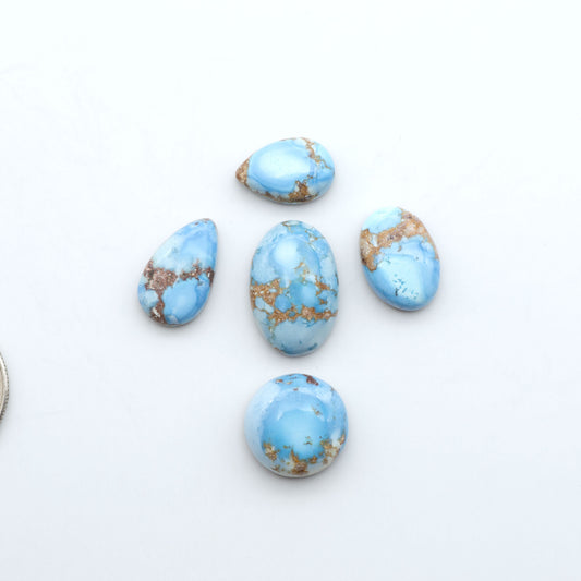 Golden Hills Turquoise cabochons, icy blue to lavender tones with chocolate matrix, polished stones on a white background with a US dime for scale