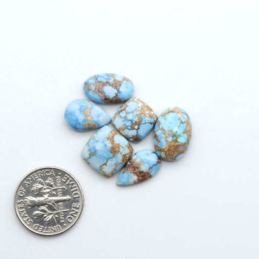Golden Hills Turquoise cabochons, icy blue to lavender tones with chocolate matrix, polished stones on a white background with a US dime for scale
