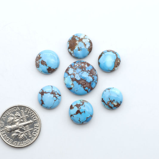 Golden Hills Turquoise cabochons, icy blue to lavender tones with chocolate matrix, polished stones on a white background with a US dime for scale
