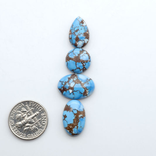 Golden Hills Turquoise cabochons, icy blue to lavender tones with chocolate matrix, polished stones on a white background with a US dime for scale