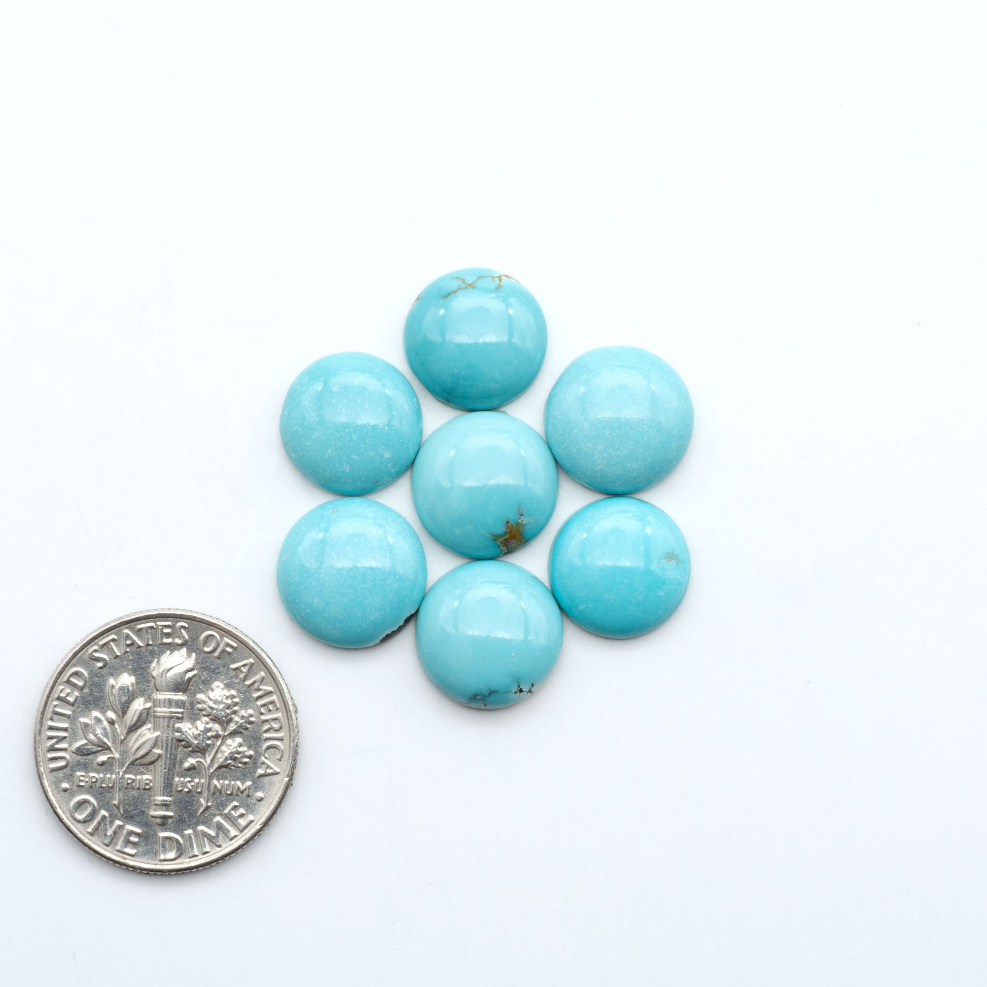 Hubei Cloud Mountain Turquoise cabochons, blue and green color with black matrix, polished stones on a white background, with a US dime for scale