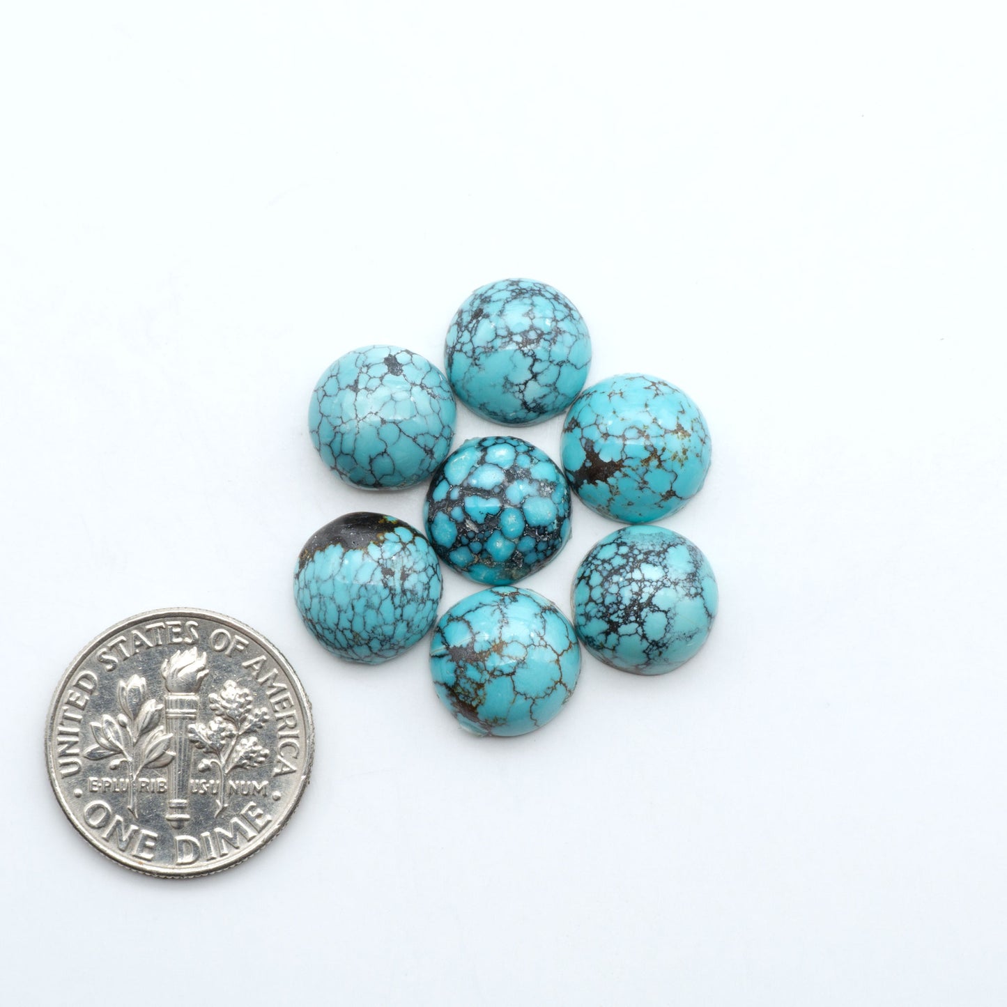 Hubei Cloud Mountain Turquoise cabochons, blue and green color with black matrix, polished stones on a white background, with a US dime for scale