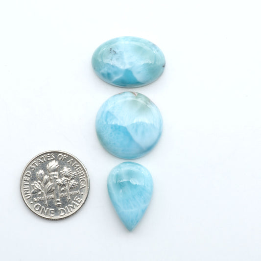 Larimar stone cabochons, cut and polished, blue and white gemstones on a white background, with a US dime for scale