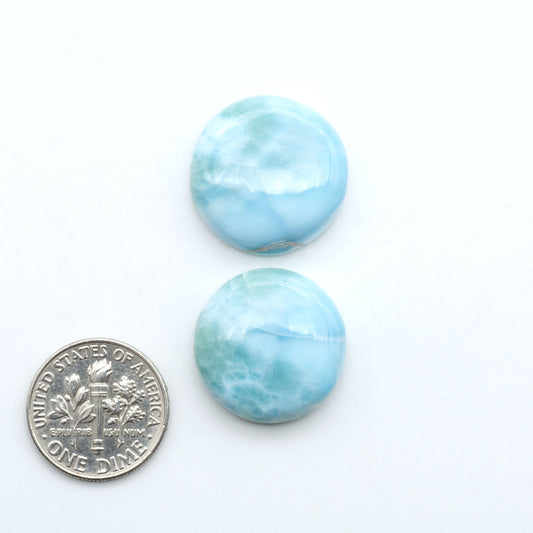 Larimar stone cabochons, cut and polished, blue and white gemstones on a white background, with a US dime for scale