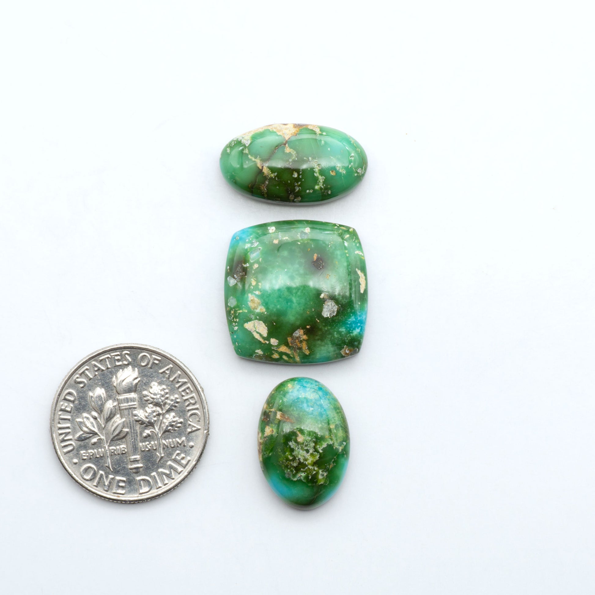 Sonoran Mountain Turquoise cabochons, blue-green color with natural matrix, polished stones on a white background, with a US dime for scale