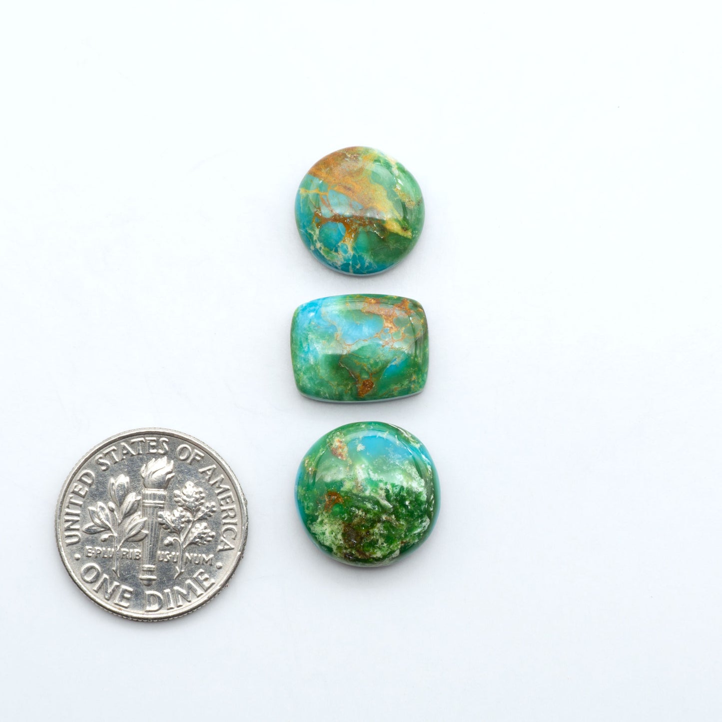 Sonoran Mountain Turquoise cabochons, blue-green color with natural matrix, polished stones on a white background, with a US dime for scale
